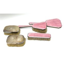 A silver and pink guilloche enamel dressing table set, comprising hand held mirror, hair brush and clothes brush, hallmarked Elkington & Co Ltd and Henry Clifford Davis, Birmingham 1932 and 1933, together with a pair of silver plated clothes brushes, with engine turned decoration and monogramed plaque, with makers mark for Adie Brothers Ltd. 