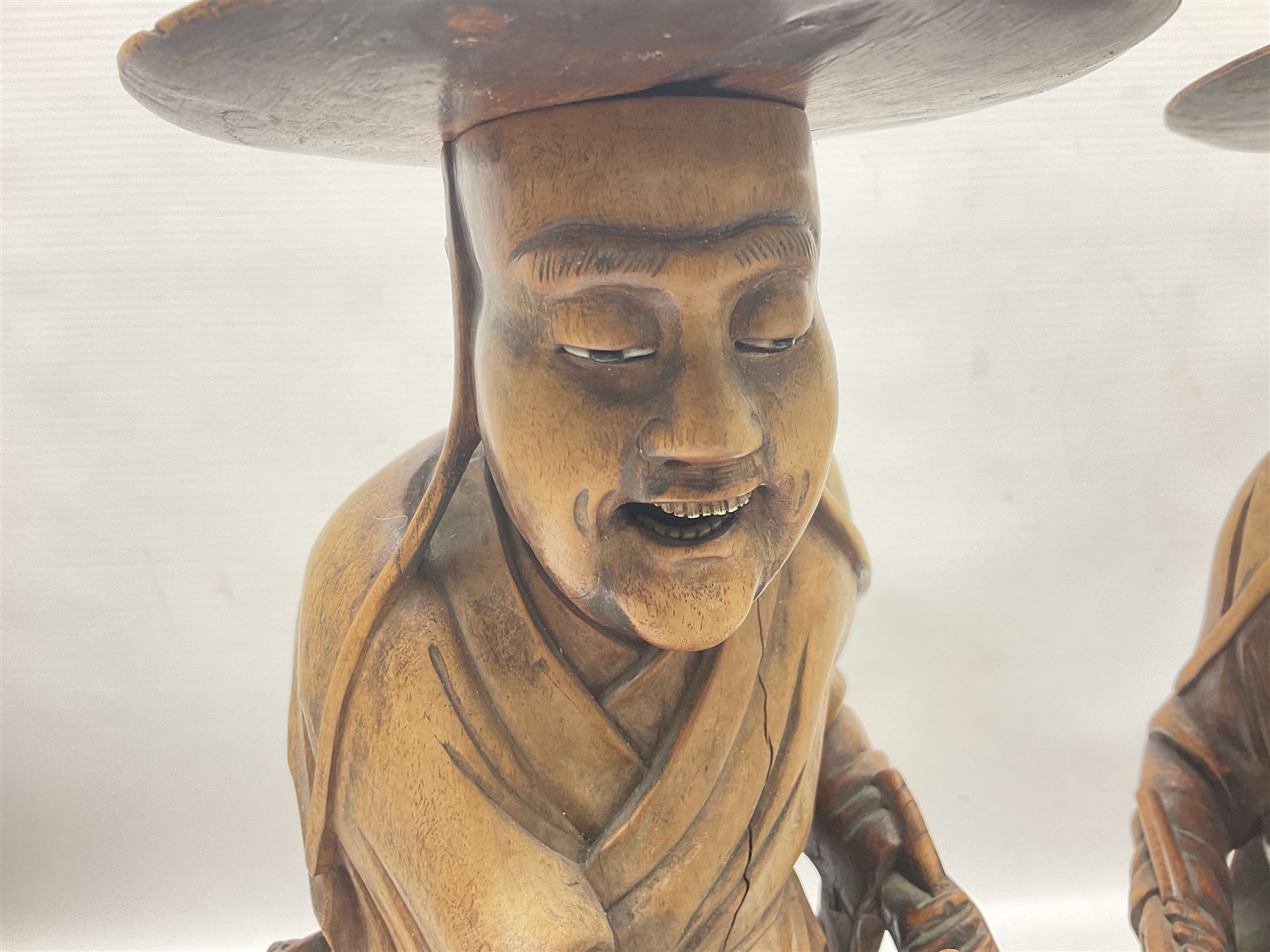 Pair of Japanese carved wooden figures, modelled as merchants in traditional dress, upon pierced naturalistic bases, tallest H39cm
