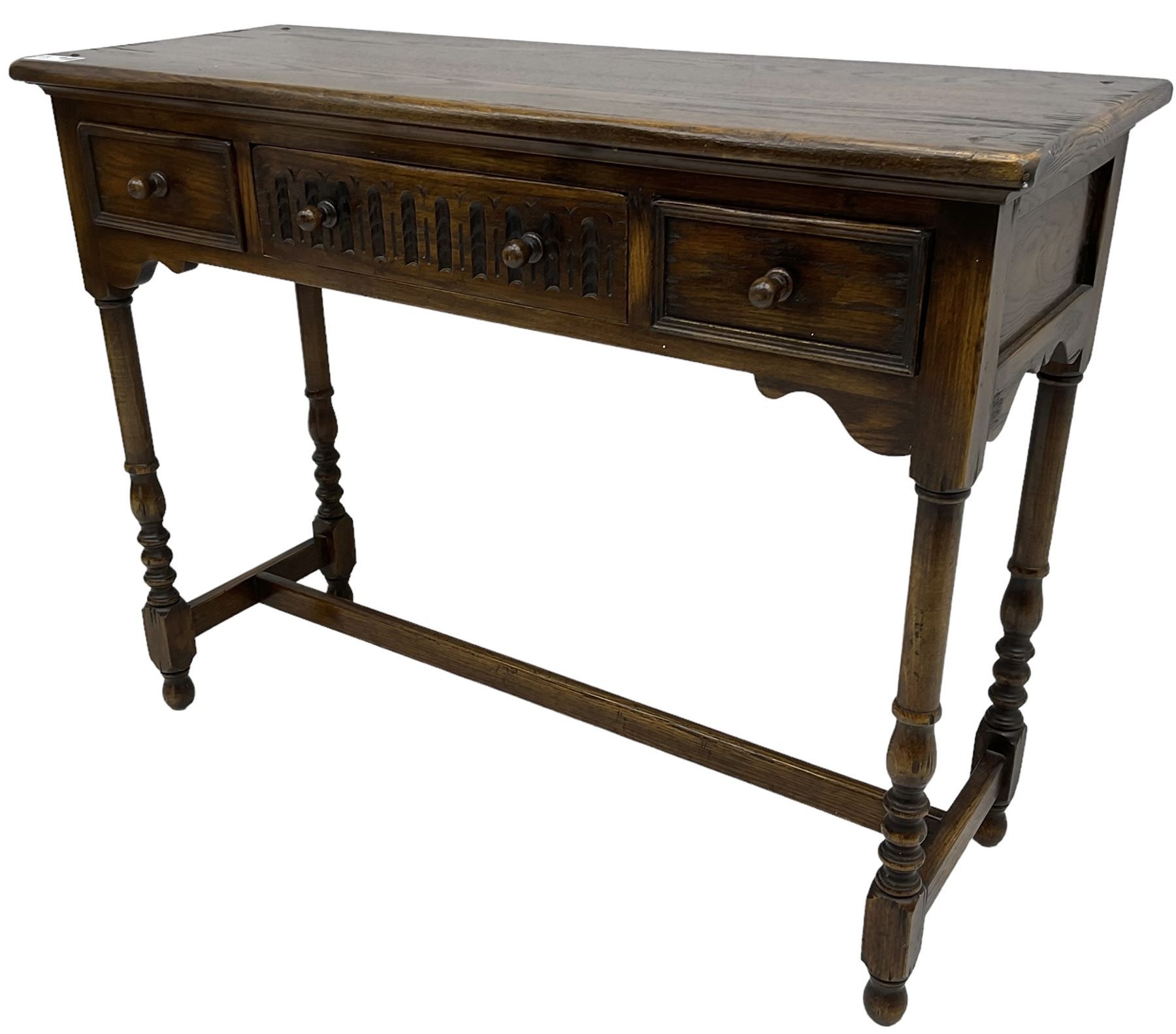 Medium oak side table, rectangular top over three drawers, on turned supports united by H-shaped stretcher rails 