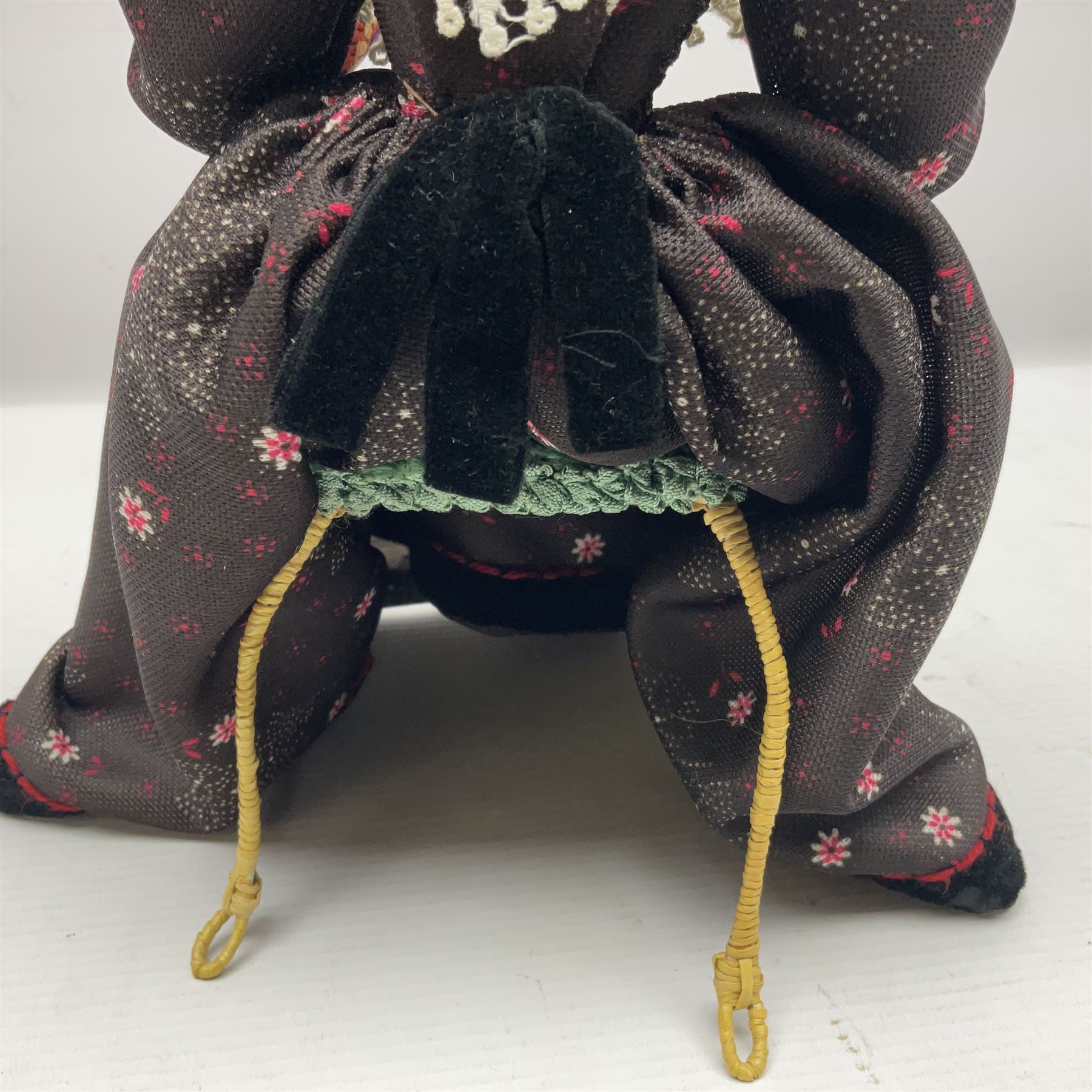 Anna Meszaros Hungary - hand made needlework figurine 'Old Lady' seated on a stool wearing a lace trimmed black/white/red floral full length dress and hat, working on a piece of lace H30cm  Auctioneer's Note: Anna Meszaros came to England from her native Hungary in 1959 to marry an English businessman she met while demonstrating her art at the 1958 Brussels Exhibition. Shortly before she left for England she was awarded the title of Folk Artist Master by the Hungarian Government. Anna was a gifted painter of mainly portraits and sculptress before starting to make her figurines which are completely hand made and unique, each with a character and expression of its own. The hands, feet and face are sculptured by layering the material and pulling the features into place with needle and thread. She died in Hull in 1998.