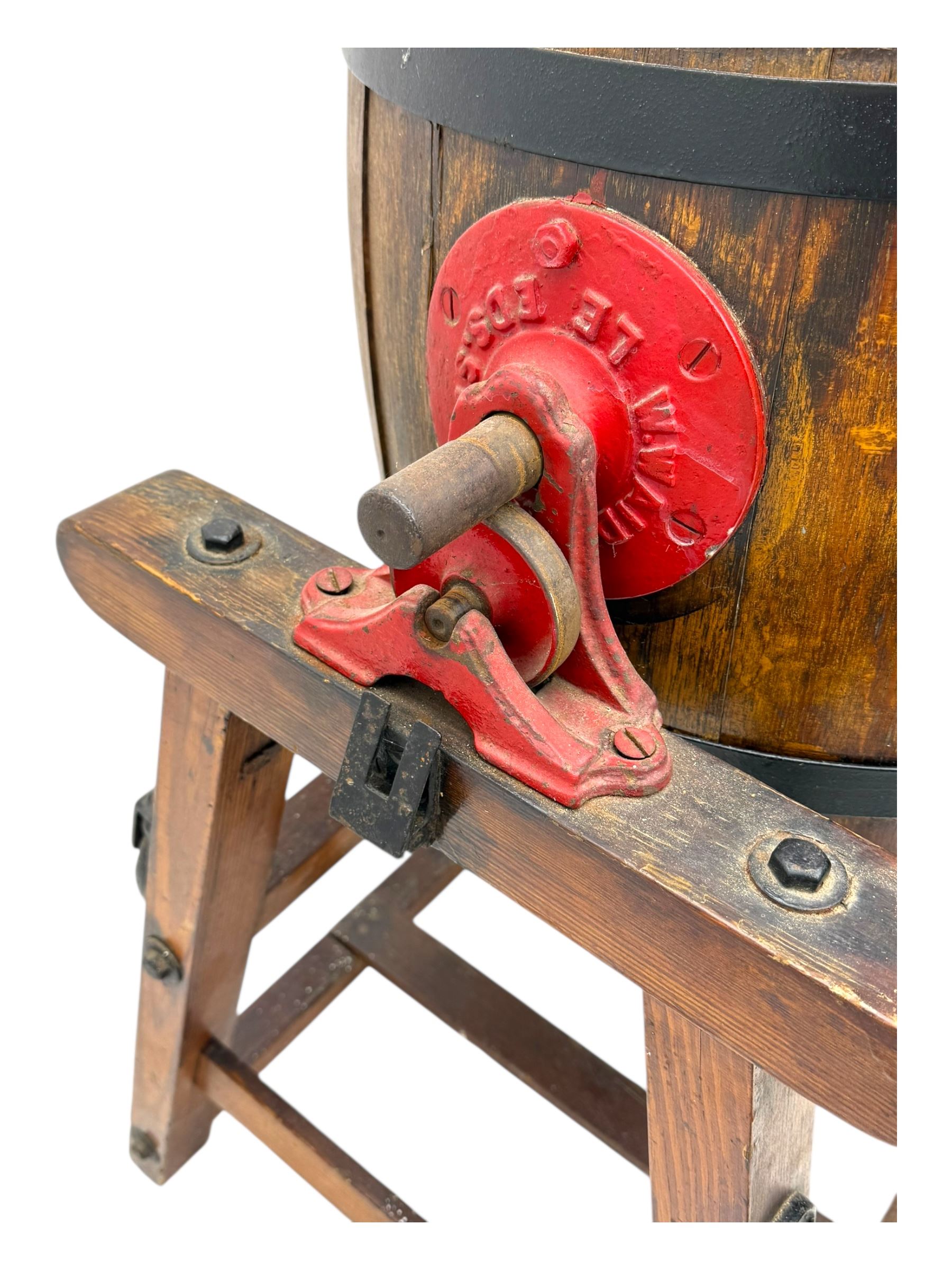 19th century oak and cast iron rotary butter churn, with coopered barrel body, domed lid with filler opening and cast iron securing arms, on tilting iron-mounted frame with crank handle and support rails