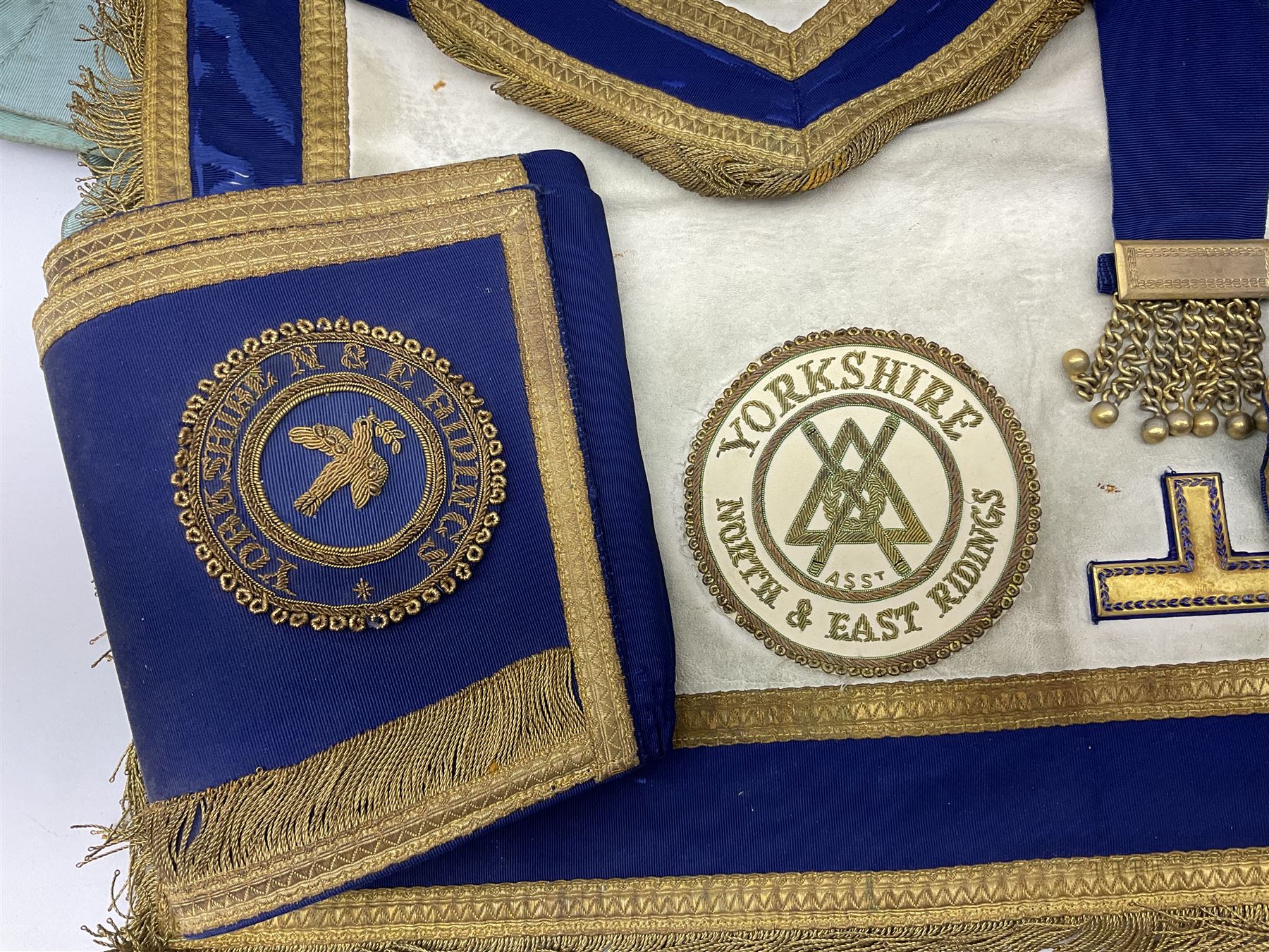 Two Masonic kid leather aprons, one with sash and cuffs, the other with sash, each marked 'Yorkshire North and East Ridings'; and three other unmarked Masonic aprons with sashes