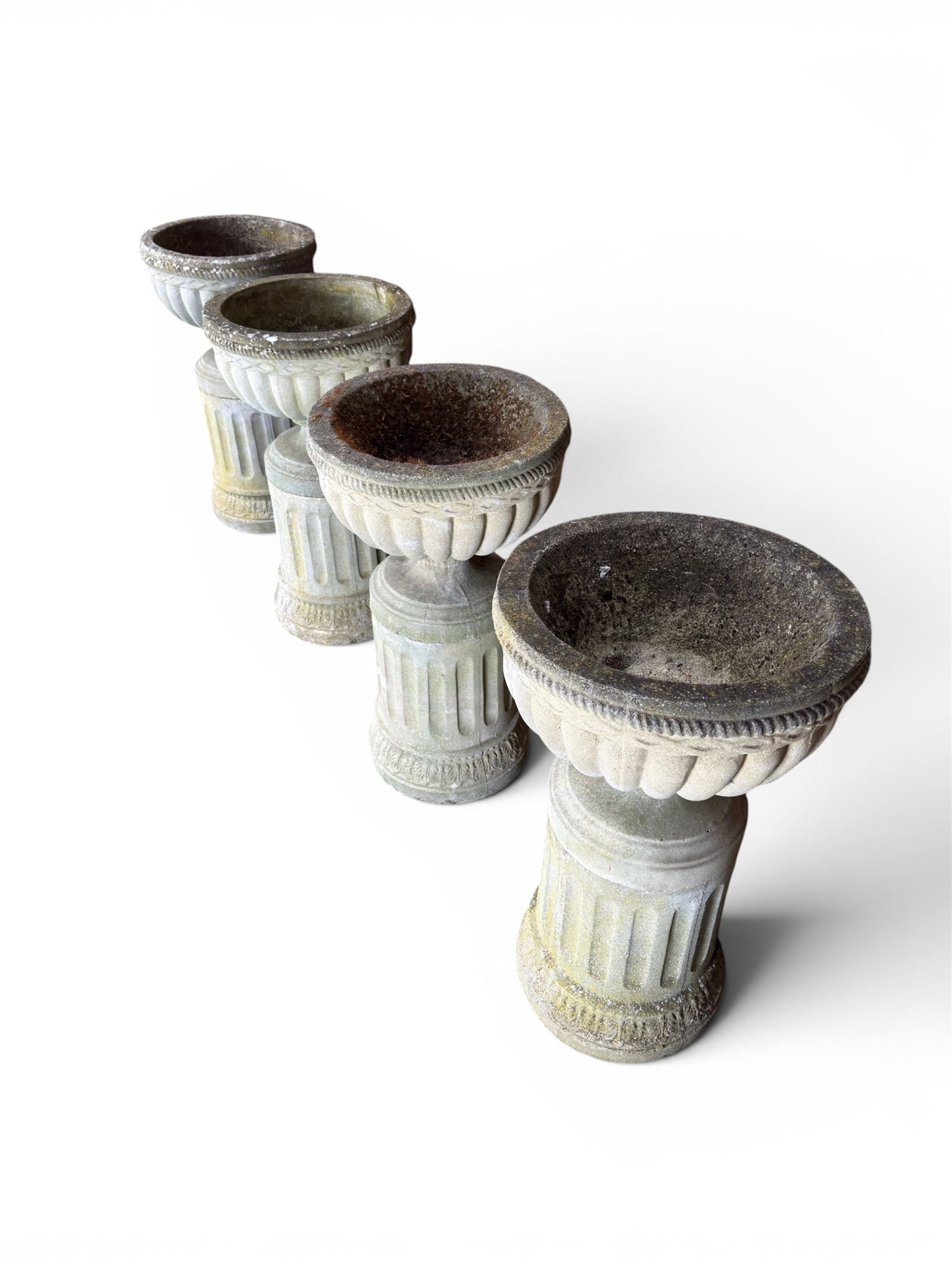 Four 20th century good quality weathered cast stone pedestal urns, circular lobed bowls with rope twist and lattice border, raised on squat base with fluted columns