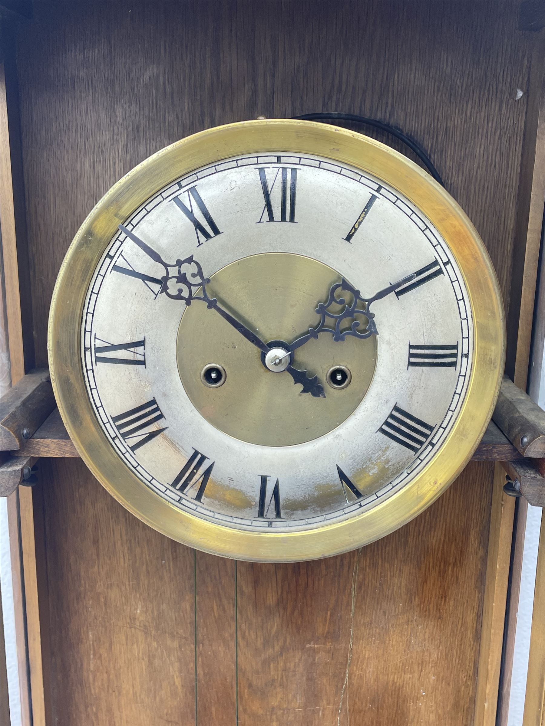 Early 20th century oak cased wall clock, the door glazed with circular convex dial glass and bevelled upright panes, circular brass and silvered Roman dial, twin train driven movement striking on coil 