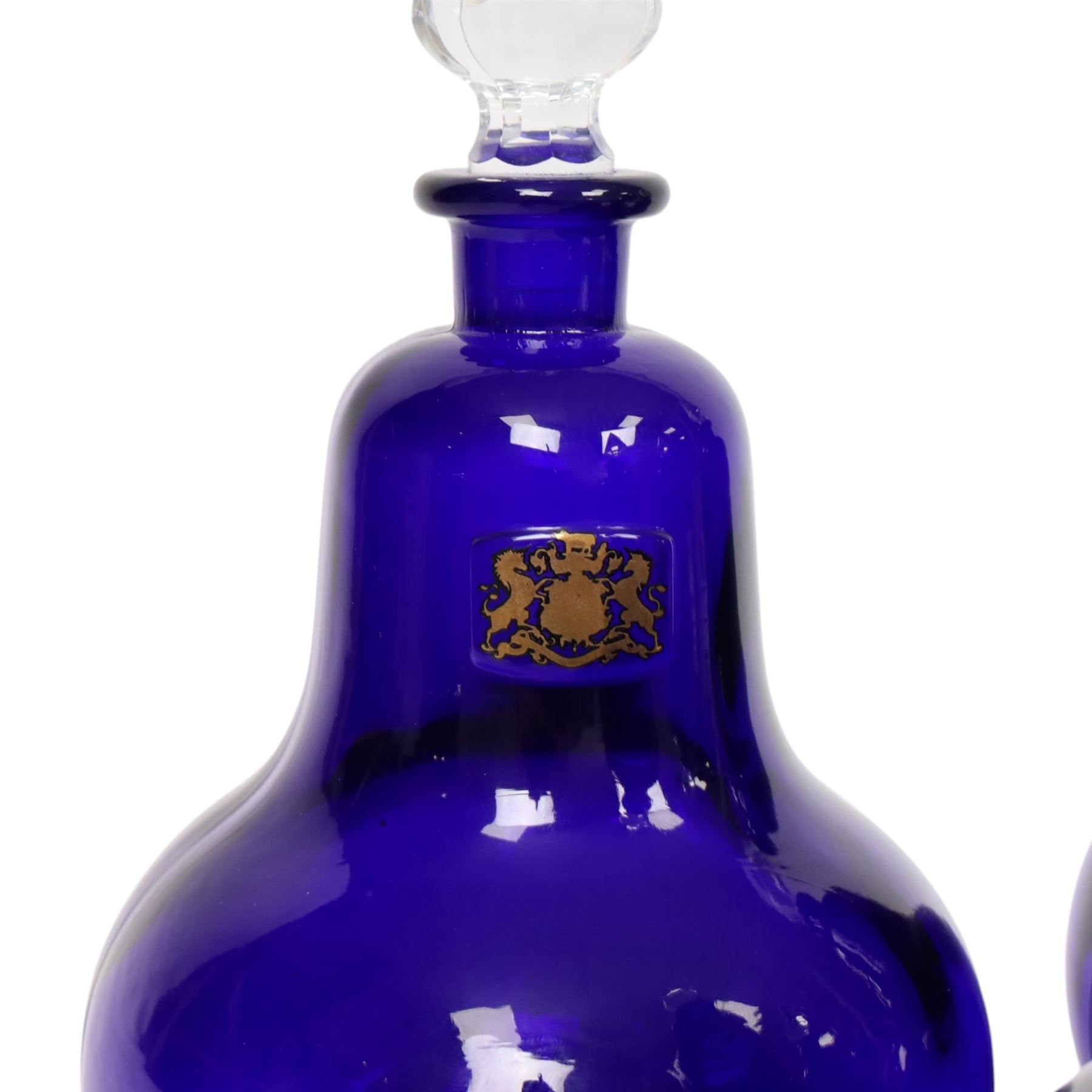 Set of four 20th century Royal Pharmaceutical Society blue glass bottles, of bellied form with clear cut glass spire stopper, each body bearing gilt label in Latin: VIN:ACET:, VIN:ANTIM:, VIN:XERIC:, and VIN:FERR:, and gilt Royal Pharmaceutical Society crest to neck, H25cm

Provenance: From the collection of the family of Peter Green, a practising pharmacist whose career spanned the mid to late 20th century. During his professional life he managed pharmacies in Yeovil, Somerset, and later Selles Chemist in Filey, North Yorkshire, before purchasing and running his own business, Peter Green Pharmacy, located in the Market Place, Malton. The bottles were displayed as part of the traditional shop fittings in both the Filey and Malton pharmacies and were retained as part of his collection.