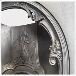 Victorian cast iron fireplace, the arched surround cast with scrolling foliate ornament and central shield-shaped cartouche, fitted with a bowed fire basket, in black painted finish