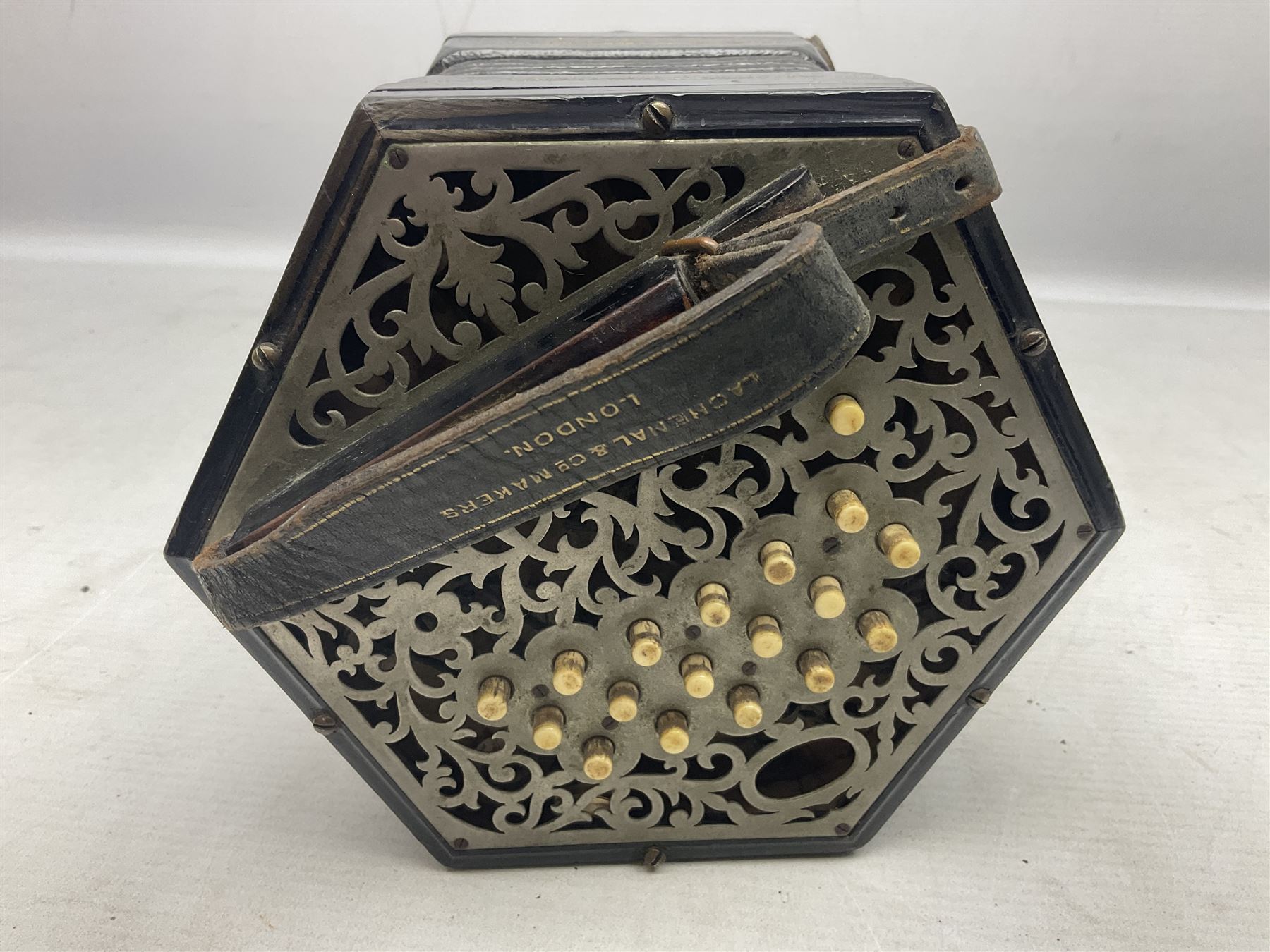 19th century Lachenal concertina of hexagonal form with fretworked nickel ends and thirty-four plus one bone buttons; straps marked Lachenal & Co Makers London and wooden handle stamped English Make Trade Mark L16cm