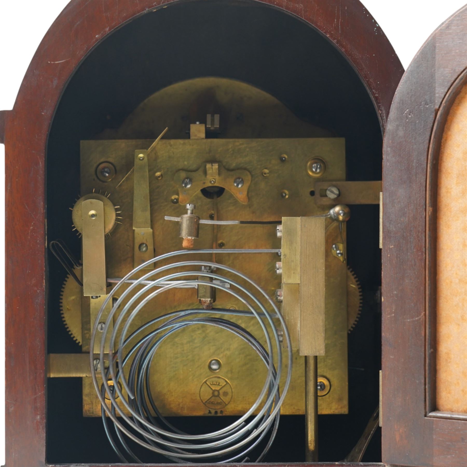 English-8-day 20th-century three train Westminster Chime Lancet clock in a mahogany case, with canted reeded quarter columns to the door and silk backed sound frets to the sides, fully silvered dial with decorative engraving and pendulum adjustment dial, silvered chapter with Roman numerals, minute track and spade hands, chiming the quarters and hours on five coiled gongs, With key, no pendulum. 
