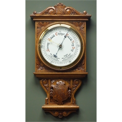 Early 20th century oak case aneroid barometer, carved scrolls and floral spandrels, with centre coat of arms crest, circular white enamel dial, H105cm  