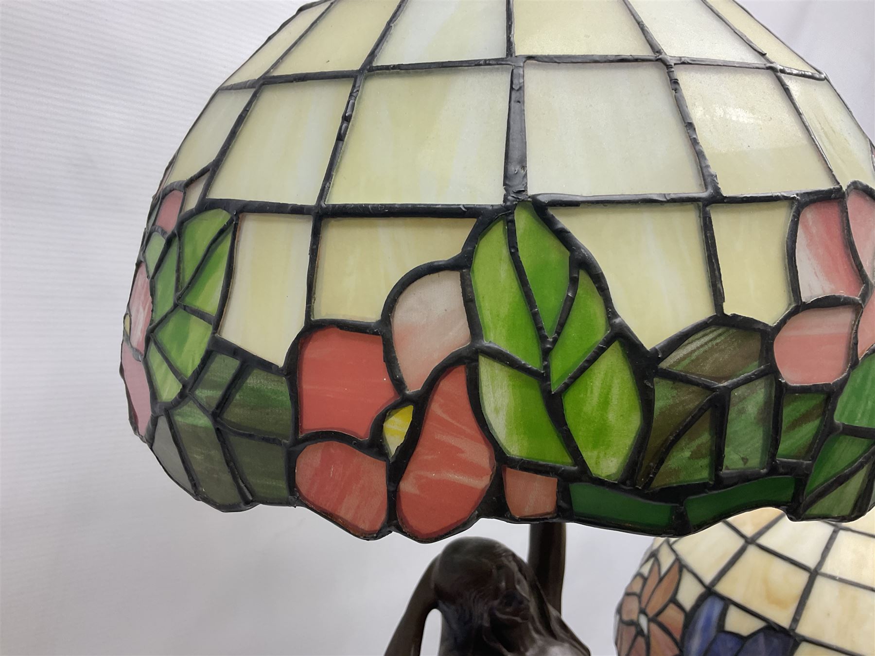 Tiffany style lamp in the form of a semi nude woman holding up a leaded lampshade together with a similar table lamp