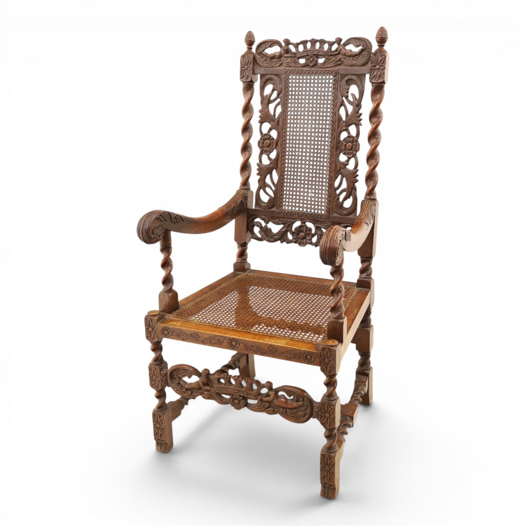 Late Victorian Jacobean Revival oak armchair, the caned back within a pierced and carved foliate frame surmounted by acorn finials, carved scroll arm supports, caned seat, on barley twist supports united by stretchers and carved front rail