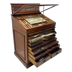 Edwardian mahogany artist's cabinet once belonging to the British artist Eli Marsden Wilson (1877-1965), raised panelled back mounted by carved brackets, sloped and hinged glazed lid enclosing paint holders and compartments, up-and-over panelled door revealing three slides, fitted with two banks of five graduating drawers with recessed brass handles, on skirted base.

Together with a quantity of artists' equipment and tools including paints, paintbrushes, charcoal, chalks, etc. and various prints relating to the life of the artist, including Quaker anti-war posters, Victorian Stevengraphs, and various chromolithographs 

Provenance: Removed from the studio of Eli Marsden Wilson. The cabinet comes to us for sale through family descent. The vendor is descendant of Marsden. Many further etchings removed from the cabinet are being sold in the Spring Art Sale, Friday 15th March 2024, Lots 265-271.

Notes: born in Ossett, Eli Marsden Wilson was the only son of Alfred Wilson, a foreman beamer, and Emma Marsden, and had five sisters. After studying at Wakefield College of Art, he moved to the Royal College of Art in London, where he became a pupil of Sir Frank Short. He had his first exhibit at the Royal Academy in 1905, the same year he married fellow artist Hilda Mary Pemberton.

A Quaker, vegetarian, and pacifist, he was a conscientious objector in World War I and as such was imprisoned in 1917 for two years. In September 1922 he was commissioned by Princess Marie Louise to produce miniature etchings for Queen Mary's Dolls' House at Windsor Castle; two such etchings are being sold in the Spring Art Sale, Friday 15th March 2024, Lot 265.