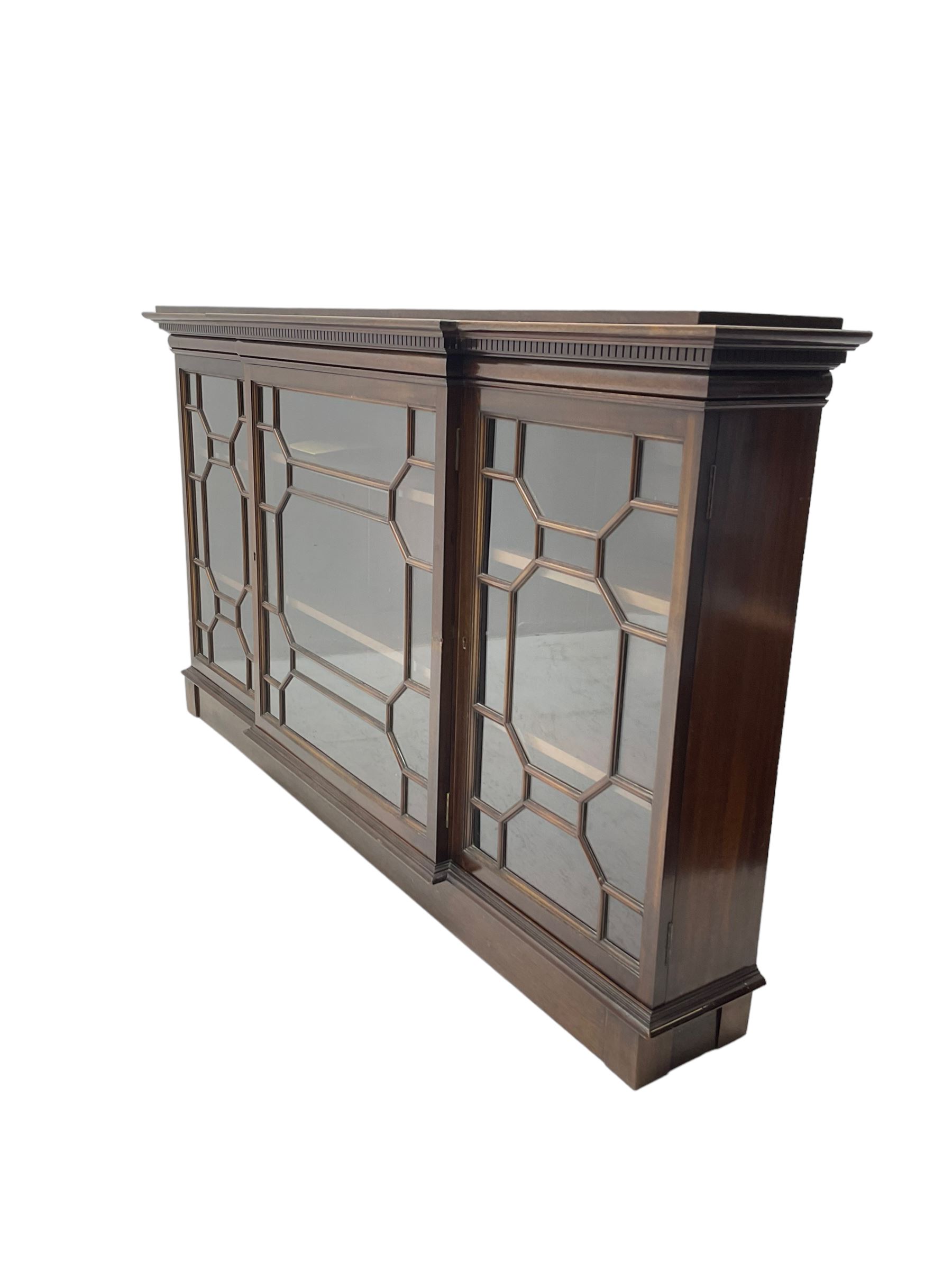 Early 20th century mahogany breakfront wall hanging bookcase, projecting dentil cornice over astragal glazed doors