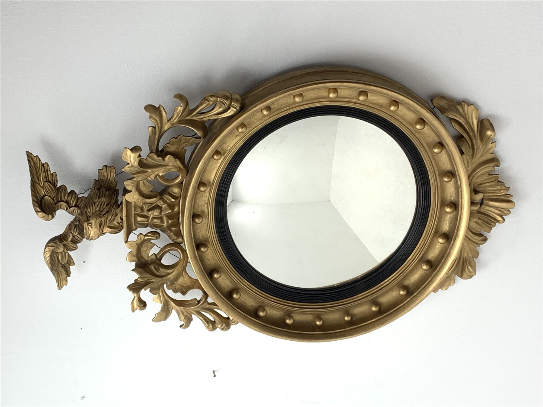 Large Regency carved wood and gesso circular convex mirror, eagle pediment on platform flanked by acanthus leaf scrolls, moulded surround and ebonised slip