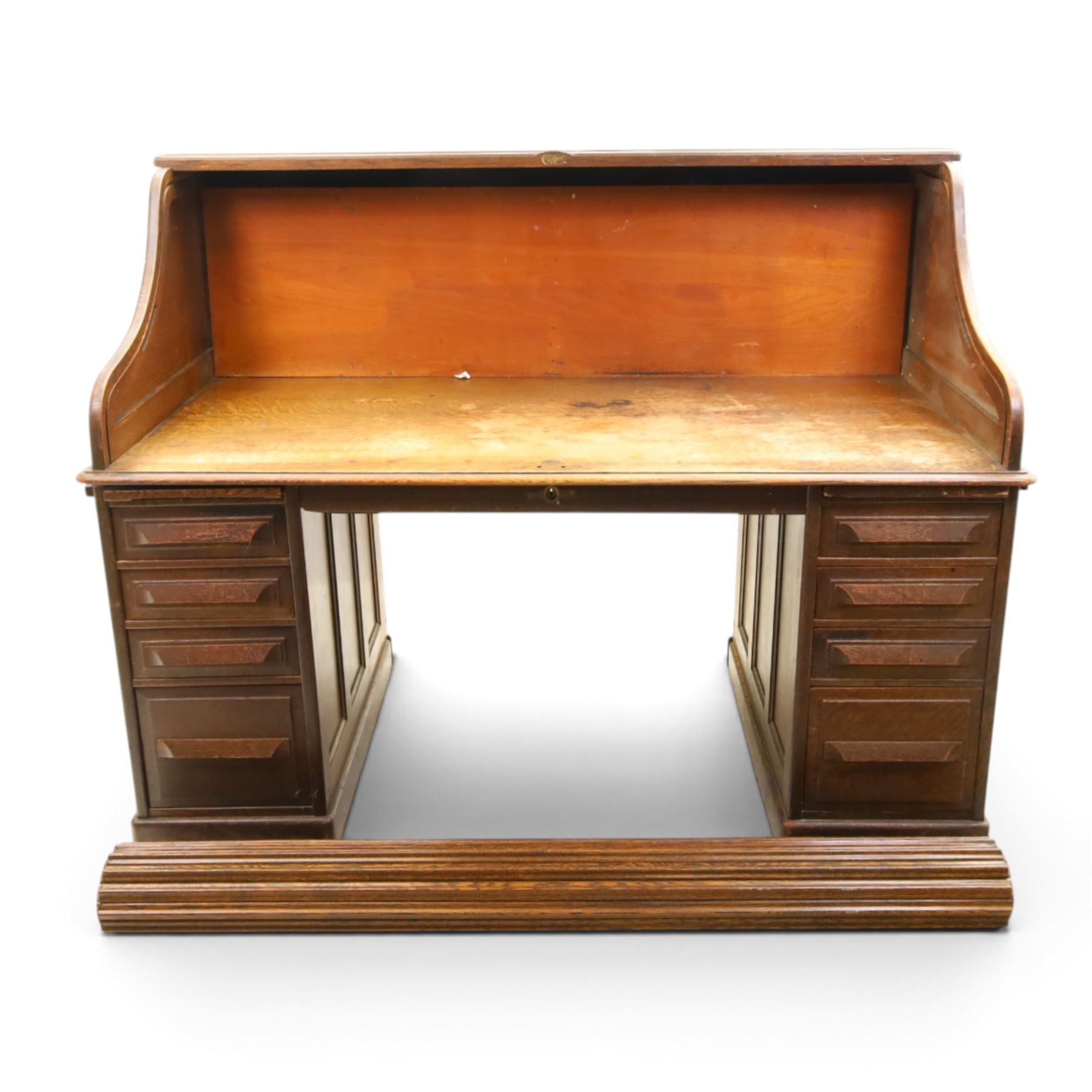 Cutler - Late Victorian oak pedestal tambour desk, the tambour shutter enclosing fitted interior, pull-out writing surface over central kneehole flanked by two pedestals each fitted with four drawers with moulded fronts, pull-out slides above, panelled sides, on moulded plinth base