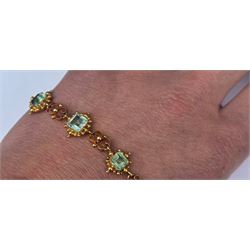 19th century gold emerald necklace, seven closed back octagonal cut and square cut emeralds, surrounded by a fancy bead setting, each spaced by a pierced scroll and bead design link, to a cable link chain necklace, with The Gem & Pearl Laboratory report