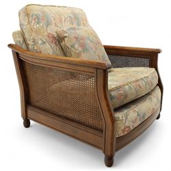 Ercol – bergère four piece suite, including armchair, two seat sofa, three seat sofa and footstool, all with removable floral upholstered cushions, the frames with side caning and rounded arm supports in stained beech

Three seat (H 87cm, D 89cm, W 196cm)
Two seat (H 87cm, D 89cm, W 137cm)
Armchair (H 87cm, D 89cm, W 87cm)
Footstool (H 28cm, D 55cm, W 55cm)