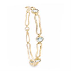 Gold blue topaz bracelet, bezel set with five oval cut topaz's, each spaced by fancy recta...