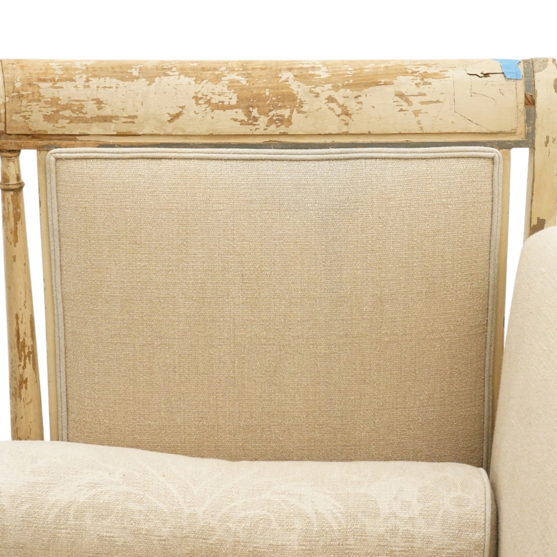 19th century French painted day bed, asymmetrical scrolled ends flanking a serpentine upholstered back, with upholstered end panels, loose seat cushions and cylindrical bolsters upholstered in beige fabric, with turned uprights with fluted detailing, moulded seat rail and lozenge-moulded corner blocks, raised on turned tapering supports
