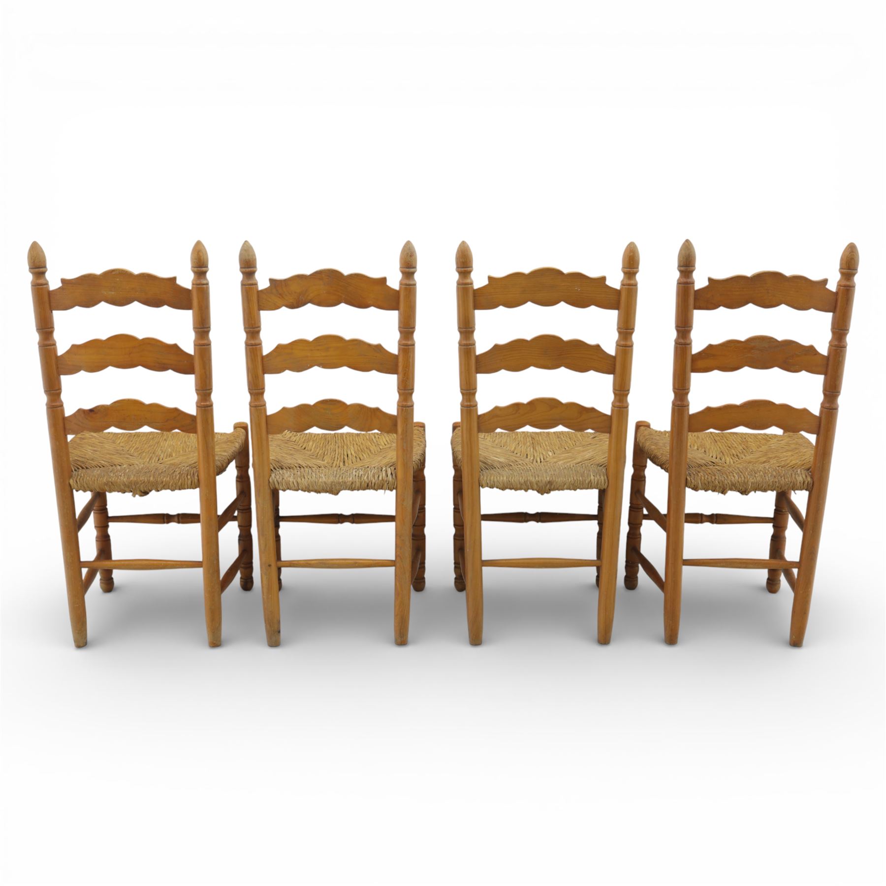 Late 20th century pine farmhouse dining table and four chairs, the rectangular plank top with rounded corners over two frieze drawers fitted with turned knob handles, raised on turned legs, the chairs with shaped ladder backs and turned finials, rush seats in a herringbone weave, on turned supports united by stretchers