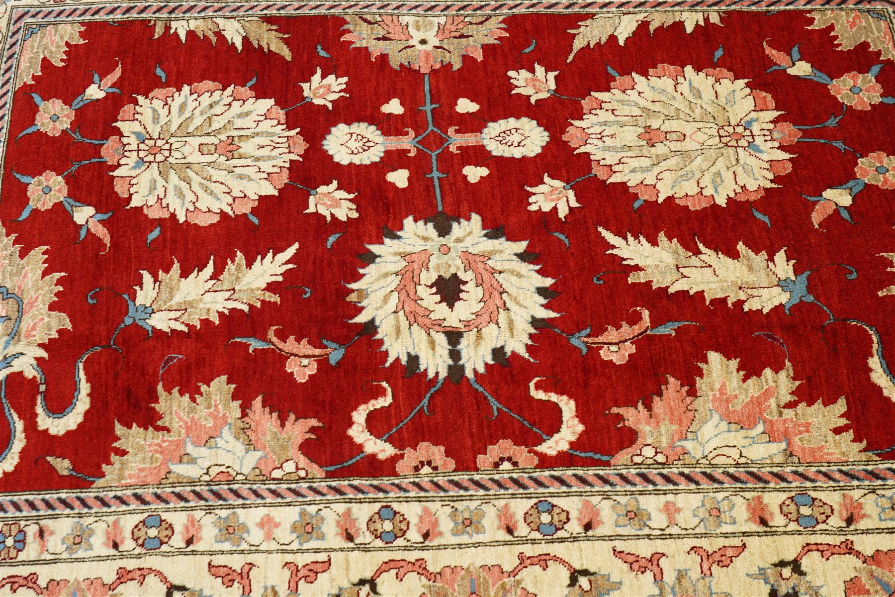 West Persian Sarough hand-knotted carpet, rich madder red field, decorated with stylized palmettes angular vinery and floral sprays within multiple borders of ivory ground and scrolling foliate decoration, with cotton fringe ends 