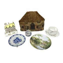 Naive seagrass tea cosy in the form of a cottage, together with pompadour moustache cup and saucer, together with a blue and white Delft plate with flower basket decor, Coalport model of Mulberry Hall and Caithness paperweight 