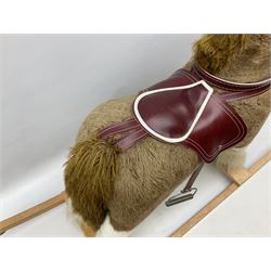 Modern plush covered rocking horse with inset eyes, simulated leather bridle and saddle with metal stirrups, on curving wooden rockers L94cm H64cm