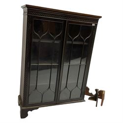 Early 20th century mahogany enclosed bookcase, frieze and uprights decorated with applied blind-fretwork, two astragal doors enclosing three adjustable shelves