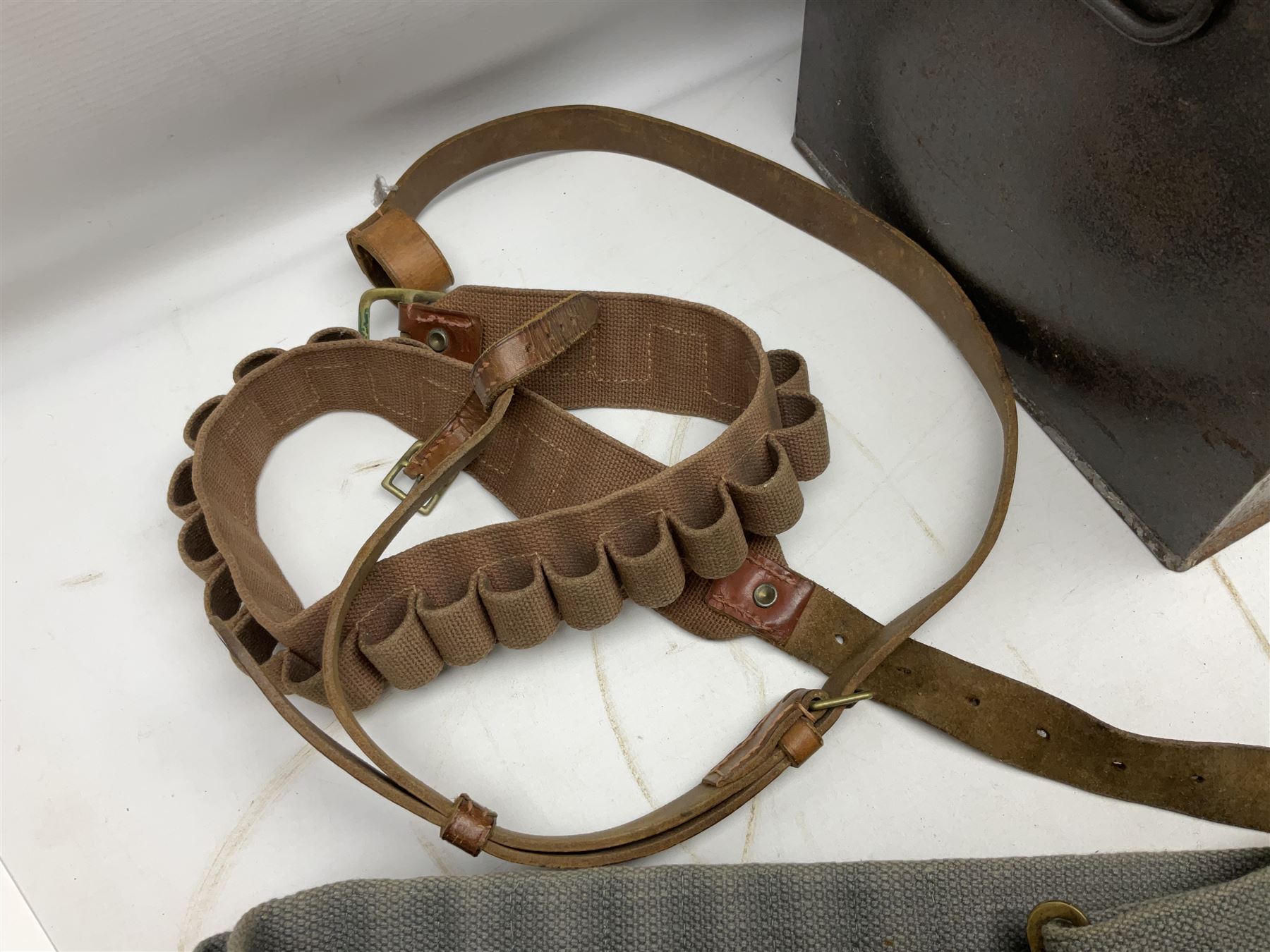 Assorted militaria including ten leather or canvas cartridge and other belts, maroon beret with 17th Lancers cap badge, modern bullet mould, leather and brass shot flask, two knives, shell cases, boomerang etc; in tin deed box