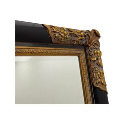 Early 20th century wall-hanging mirror, rectangular bevelled mirror plate within ebonised frame, gilt mounts to the corners carved with floral motifs 