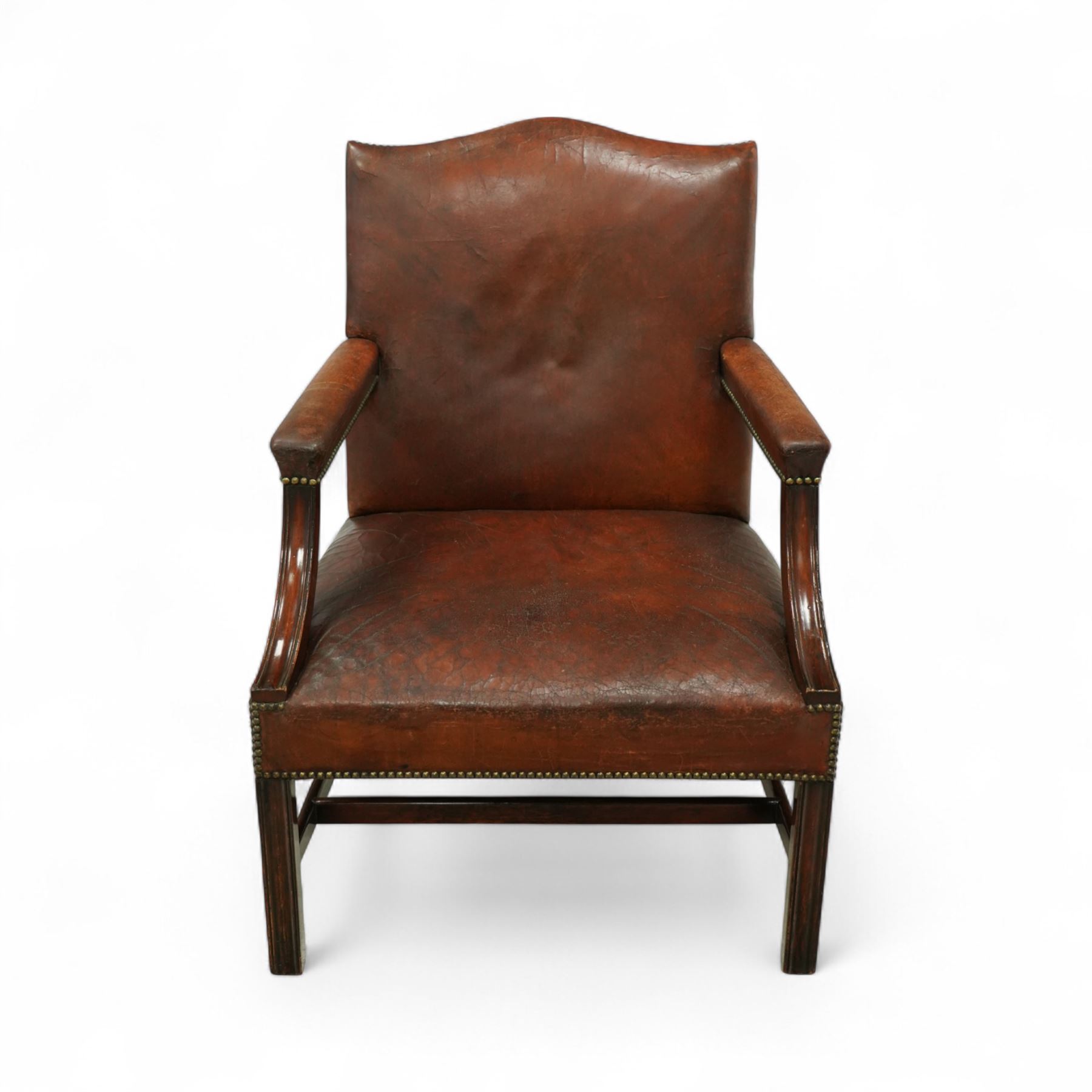 Early 20th-century Gainsborough-style library armchair, padded back, arms, and seat, brass button upholstered in brown leather, on square tapered front legs united by a stretcher 