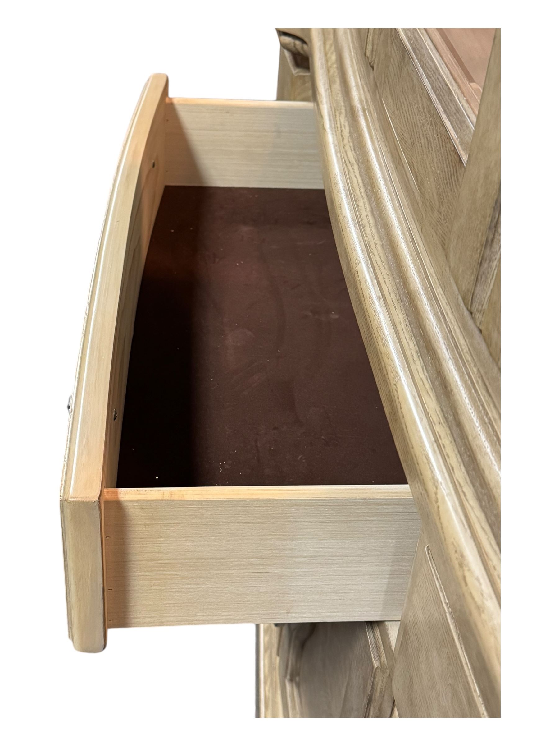 Brunswick - washed oak finish illuminated display cabinet, upper section with four glass-panelled doors enclosing glass shelving, base fitted with two drawers over four paneled cupboard doors, each fitted with distinctive round metal handles, raised on plinth base