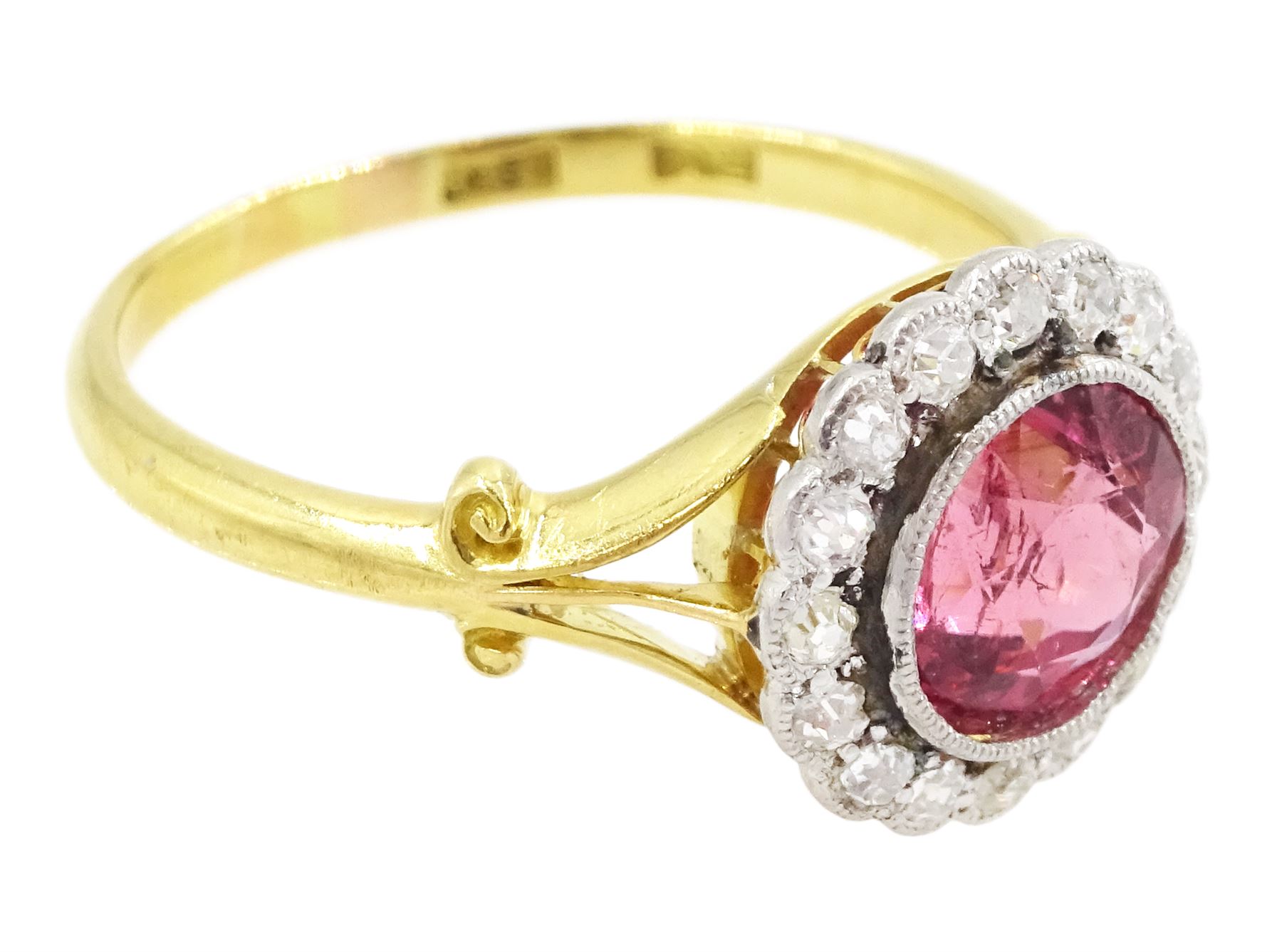 Early 20th century gold tourmaline and diamond cluster ring, milgrain set single stone pink tourmaline of approx 1.35 carat, surrounded by sixteen old cut diamonds, to a split design scroll shank, stamped 18ct, total diamond weight approx 0.30 carat