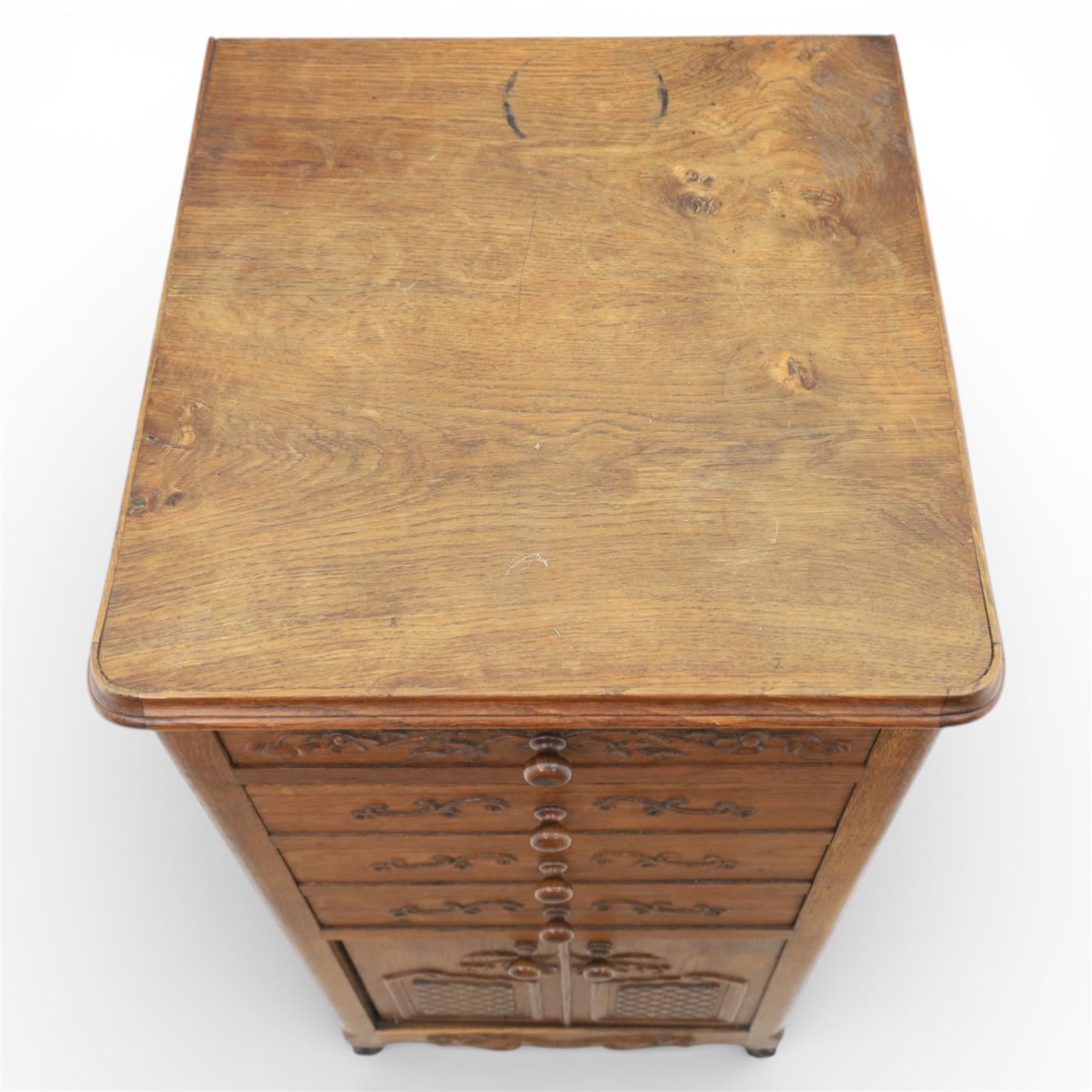 20th century French style oak bedside chest of pedestal form, the top with rounded moulded edge with drop leaf to the back, above five carved drawers with applied scroll ornament and turned knobs, the cupboard base with twin carved doors with diamond lattice panels, with shaped apron and bracket feet