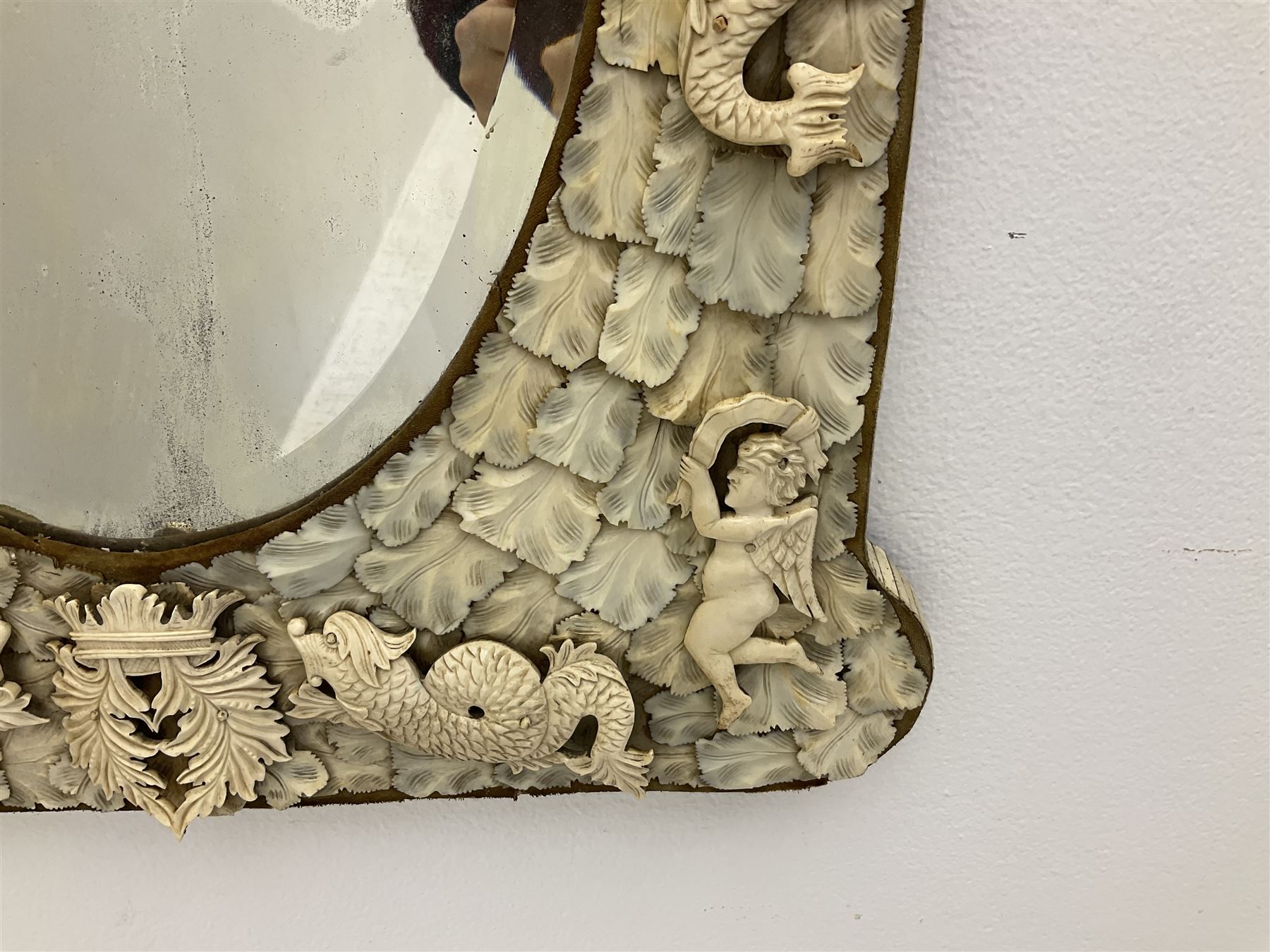 Pair 19th century French Dieppe bone and ivory wall mirrors, the oval bevelled mirror plates within rectangular frames with shaped tops, profusely decorated with ivory leaves, further detailed with carved bone armorial type crest inscribed 'SGOTORVM', putti, fish and mask heads, H81cm W48cm