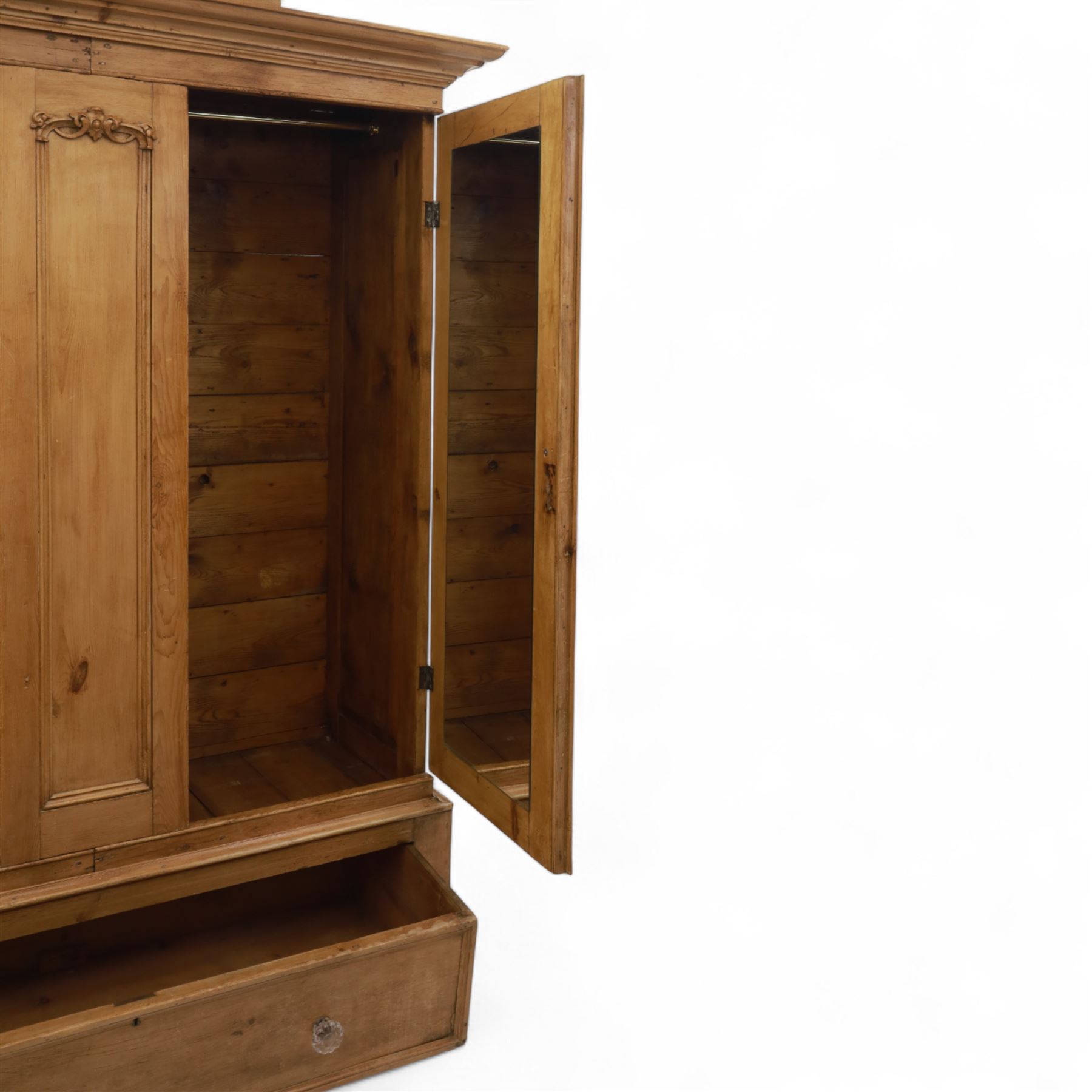 Late 19th century pine wardrobe, with stepped cornice over triple panelled doors, applied foliate carvings to outer panels, raised over a separate pine plinth drawer with moulded facia and twin glass pulls
