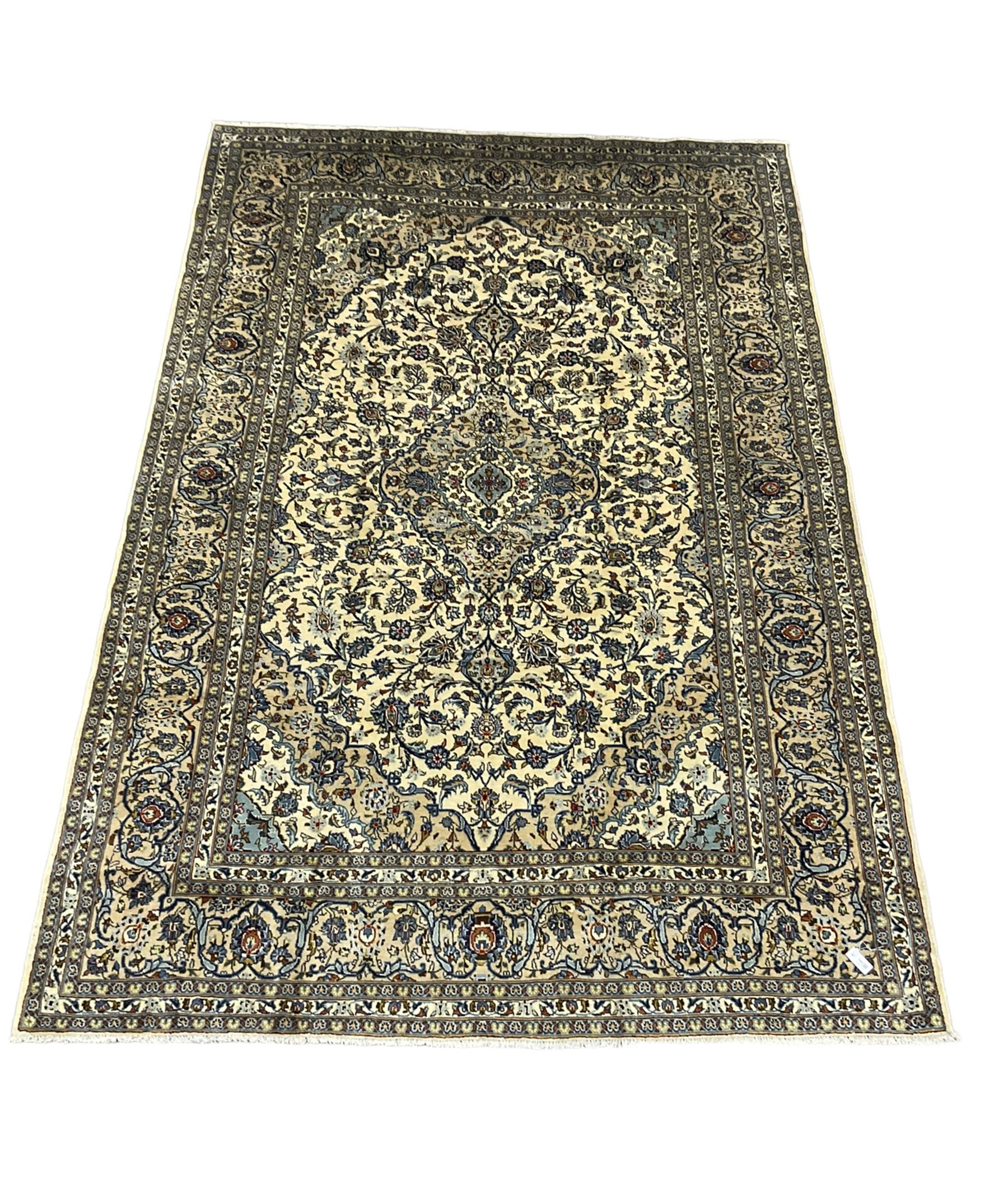 Persian Kashan ivory ground carpet, the field decorated profusely with interlacing branch and stylised plant motifs, scrolling border with overall floral design 