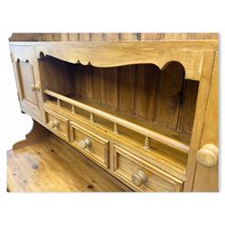 Traditional vintage pine kitchen dresser with scrolled cornice and rack with long shelf above a galleried shelf flanked by three short drawers and two cupboards, the base with three long drawers above three cupboards on plinth base  