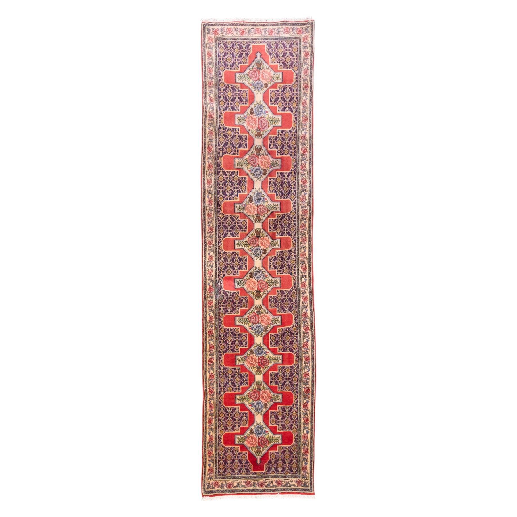 North West Persian Senneh hand-knotted runner, field with a central stepped medallion design in madder red and cream, in a series of linked lozenges filled with finely composed floral sprays and stylized roses, surrounded by densely patterned repeating geometric motifs, enclosed within a narrow main border with floral meander, flanked by multiple guard stripes, with fringe ends 