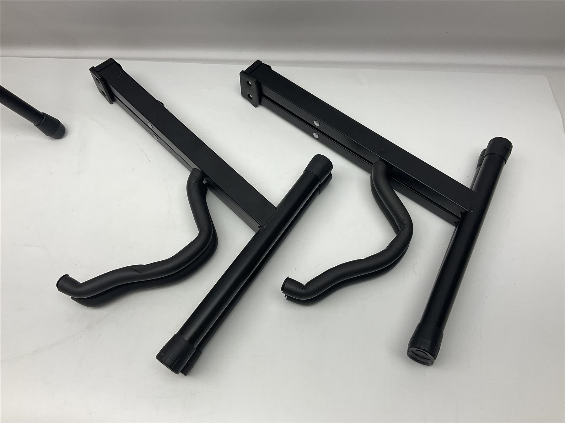 Four folding tubular guitar stands, two by RockJam; and folding tubular saxophone stand (5)