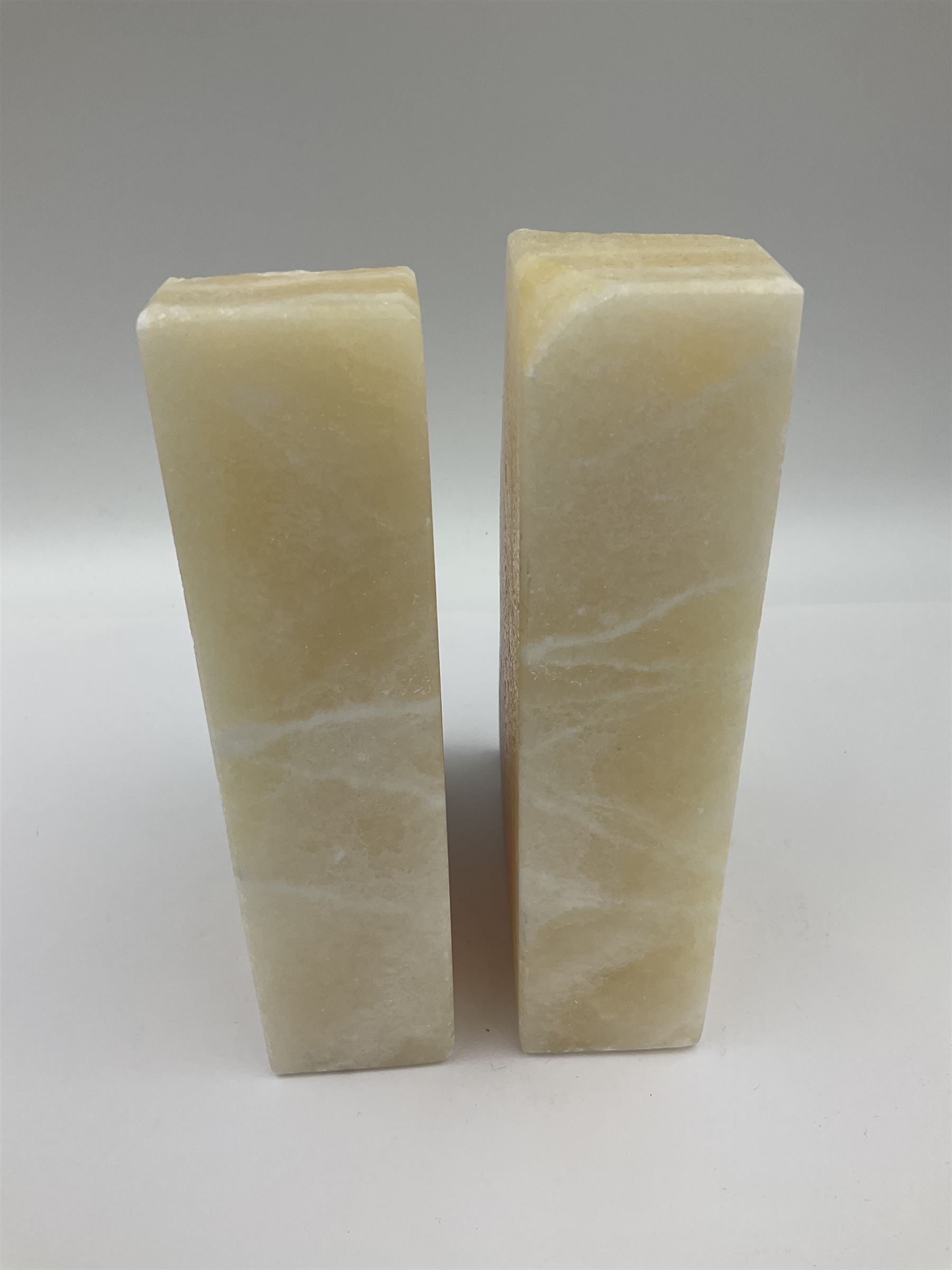 Pair of honey onyx bookends of rectangular form with polished to three sides with a raw outer edge, H18cm 
