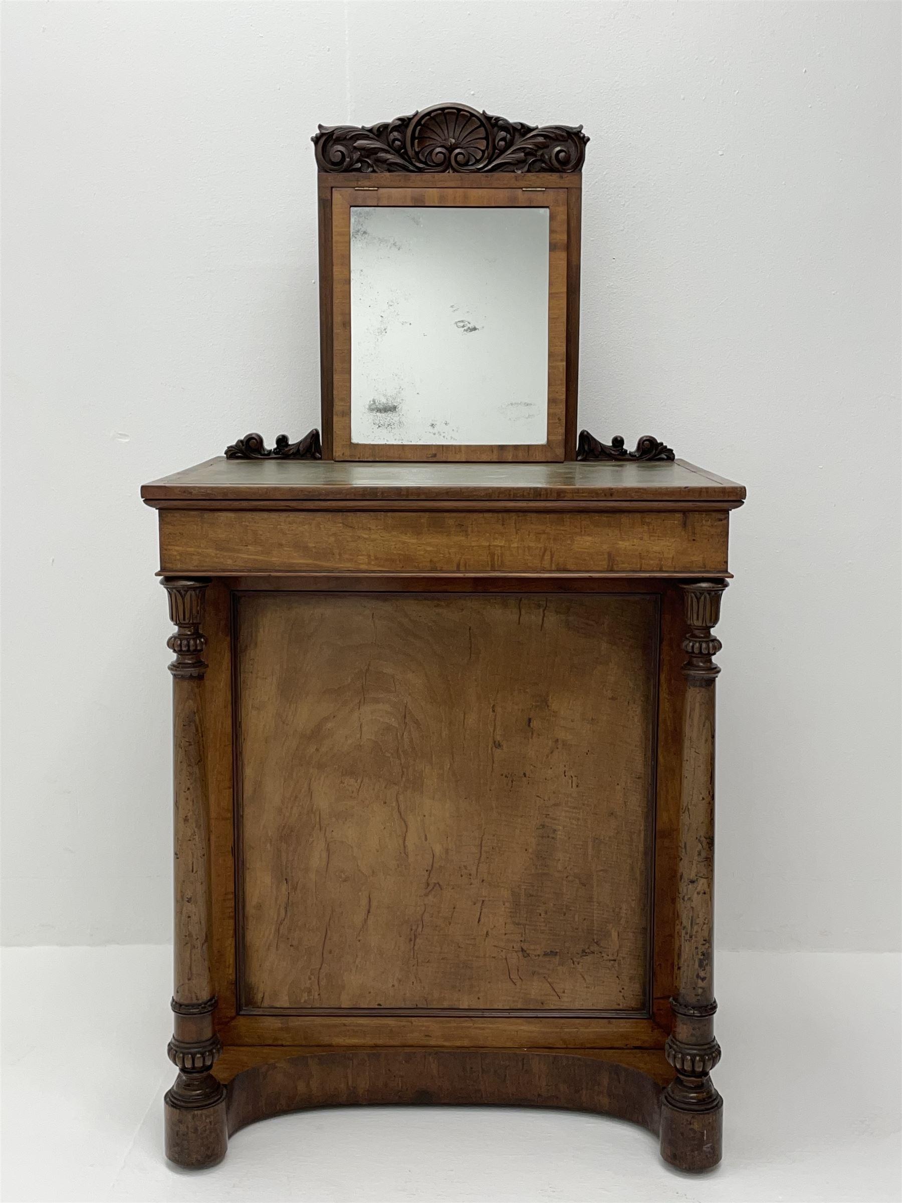 Early Victorian figured mahogany dressing cabinet, the raised shell and scroll carved back lifts to reveal rectangular easel mirror with mahogany band, flat rectangular top with tooled leather inset, slide at each side with matching leather inset, full width drawer above cupboard enclosing a series of five drawers, turned front supports, panelled front, sides and back
