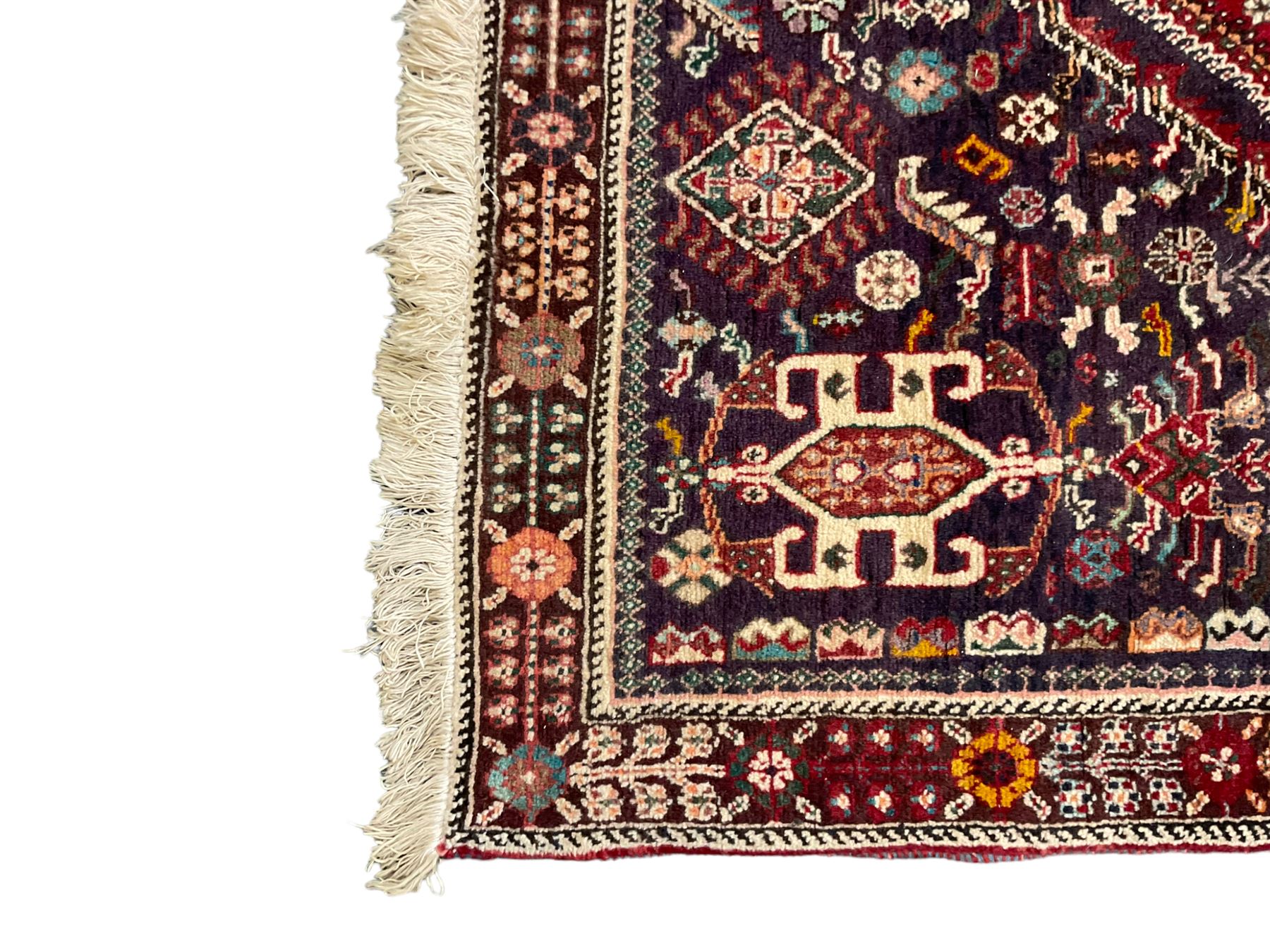 Persian Heriz crimson ground rug, field with large central lozenge surrounded by stylised plant motifs in a mauve background, guarded border with repeating foliage