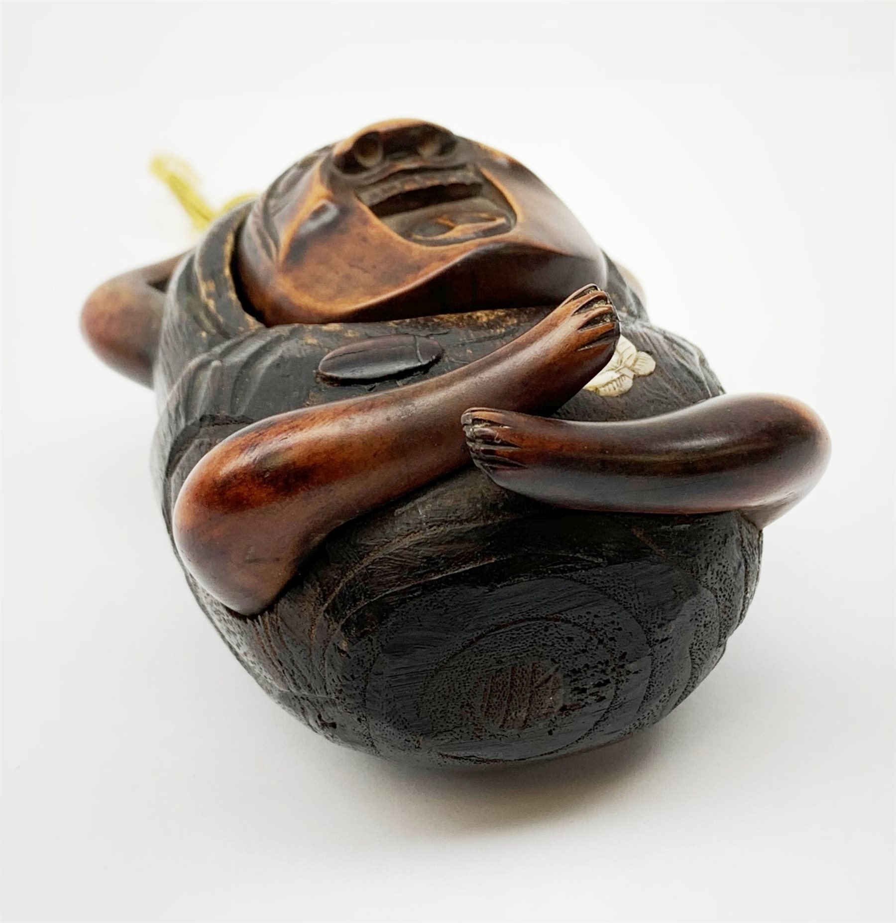 A Japanese carved soft wood inro, modelled as a streching and yawning figure, possibly Daruma, detailed with insect, inset mother of pearl butterfly, and glass eyes, H10cm. 