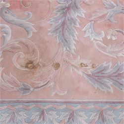 Large late 20th century Aubusson style wool carpet, peach and pastel toned field with central floral medallion enclosing scrolling acanthus and and foliate sprays, surrounding field decorated with further stylized foliage and and floral ornament, within shaped reserves and indigo corner spandrels, enclosed by narrow guard border, cotton fringe ends