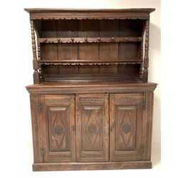 18th century oak dresser, the carved raised back fitted with two shelves and eight turned hooks over base with cushion frieze and lozenge carved panel, flanked by two matching panelled doors enclosing plain interior, on a skirted base