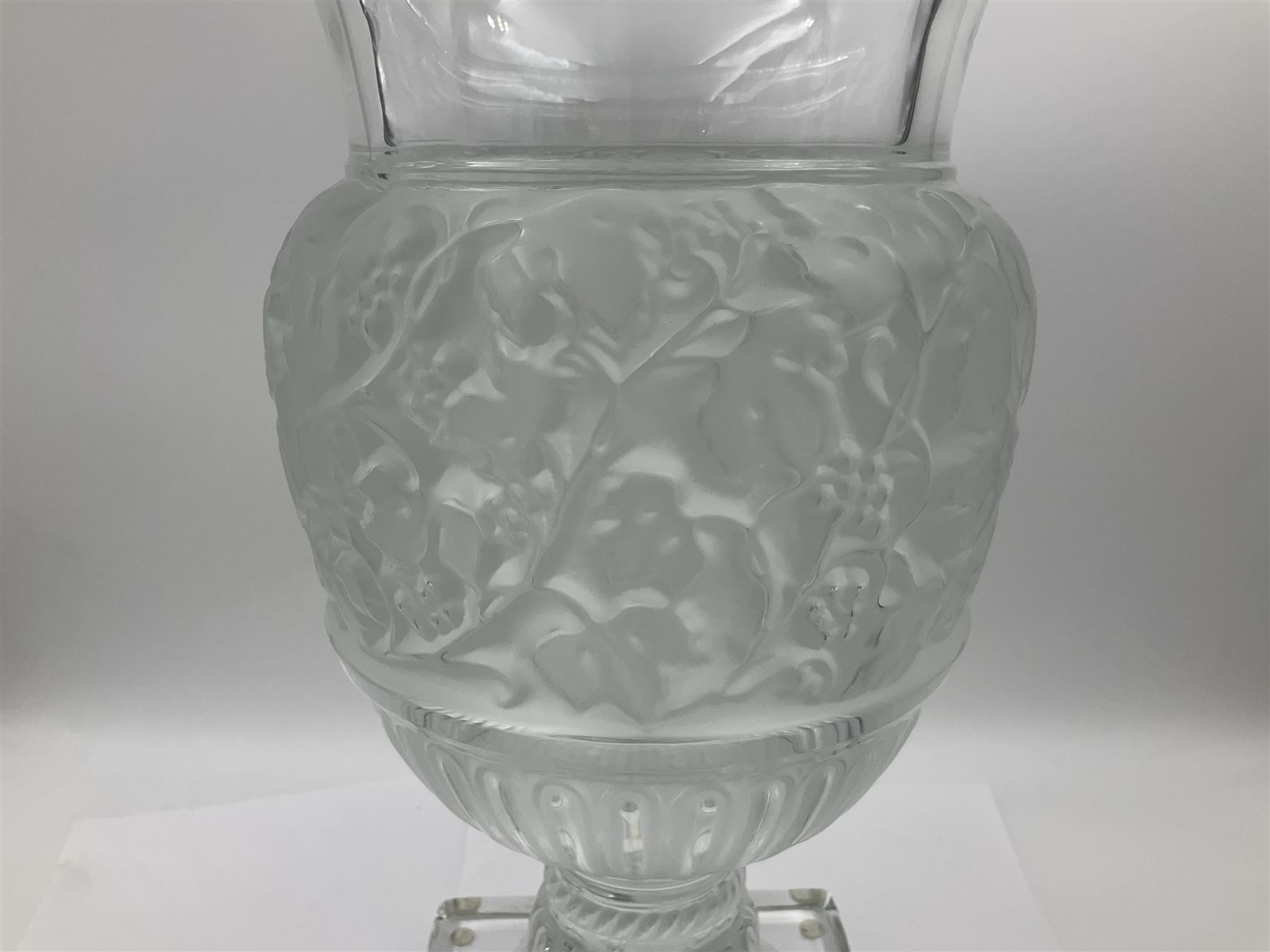 Large and impressive Lalique Versailles pattern glass vase, of classical baluster form with gadrooned flared rim, the body moulded in relief with fruiting vines above part fluting, upon a spreading circular foot with moulded decoration, and plain square plinth base, signed Lalique France to side of plinth, overall H35cm, with original box 