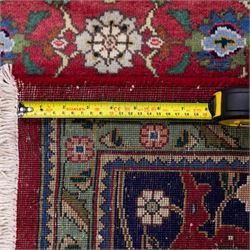 North West Persian Tabriz hand-knotted carpet, herati-type field in deep red with an all-over field densely decorated with scrolling floral sprays and palmettes on a lattice ground enclosed by a dark blue main border filled with stylized floral motifs and interlacing tendrils flanked by multiple guard stripes, with cotton fringe ends 