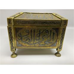 Late 19th century Damascus Cairoware Quran box, of square form with canted hinged cover, upon four circular pad feet, the brass exterior inlaid with silver and copper script and decorative detail, opening to reveal a marquetry lined interior, H15.5cm W19cm D19cm