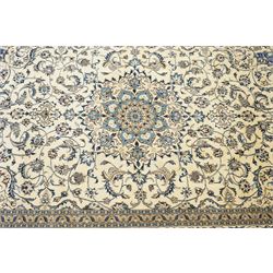 Central Persian Nain hand-knotted carpet, ivory field with central radiating medallion, issuing an all-over design of scrolling vines, palmettes, and delicate floral sprays with conforming spandrels, enclosed by a foliate border, framed by multiple guard stripes, with cotton fringe ends 